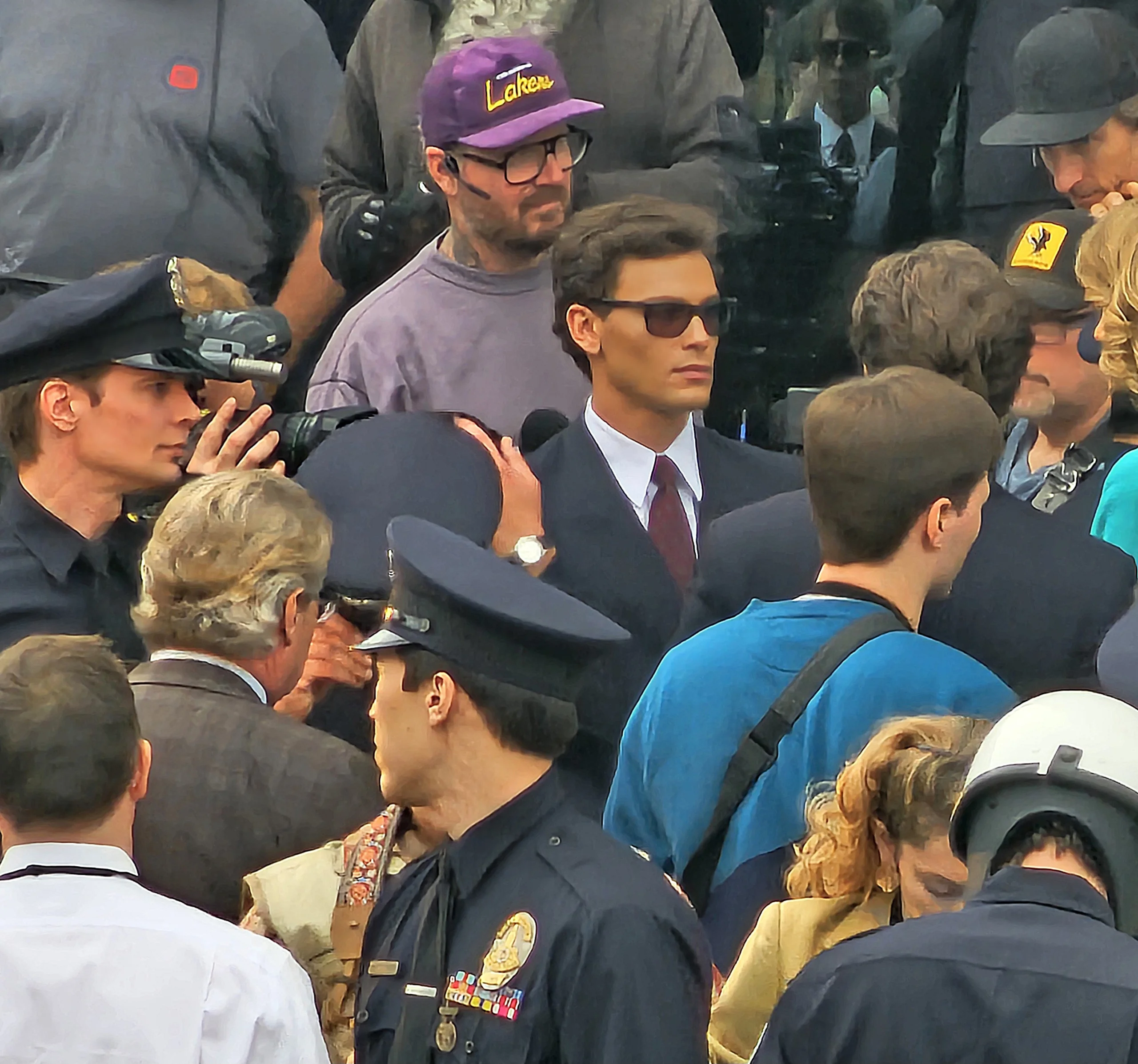 Monstros: a história de Lyle e Erik Menendez filmando a primeira cena de tribunal ao ar livre com os atores Cooper Koch e Nicholas Alexander Chavez em ternos enquanto a imprensa e a polícia caminham com eles dentro de um local em Los Angeles, 24 de janeiro de 2024