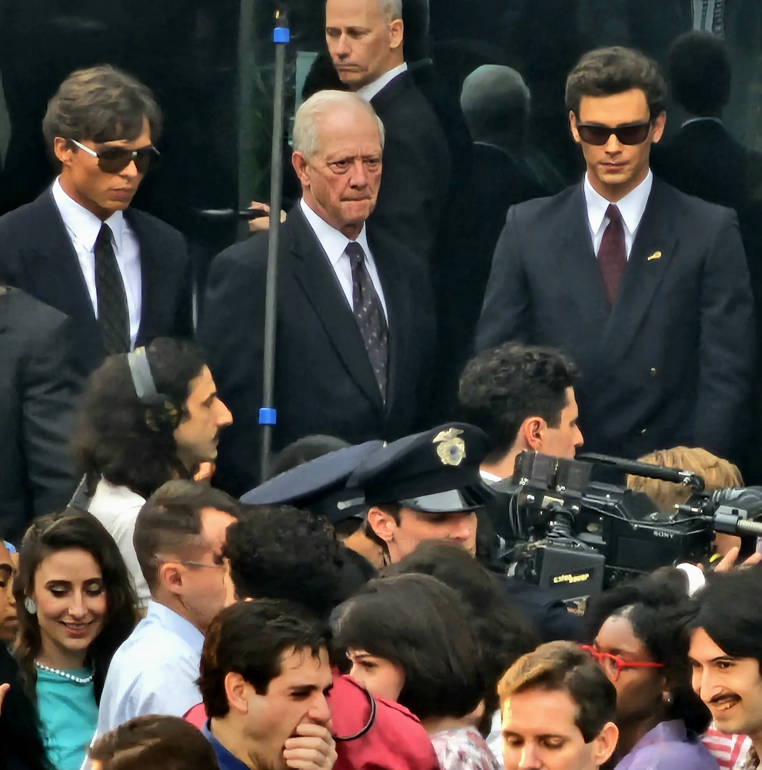 Monstros: a história de Lyle e Erik Menendez filmando a primeira cena de tribunal ao ar livre com os atores Cooper Koch e Nicholas Alexander Chavez em ternos enquanto a imprensa e a polícia caminham com eles dentro de um local em Los Angeles, 24 de janeiro de 2024